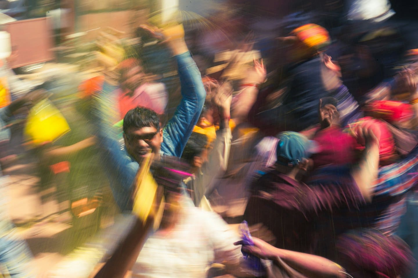 A man in sunglasses smiles while people celebrate outdoors.