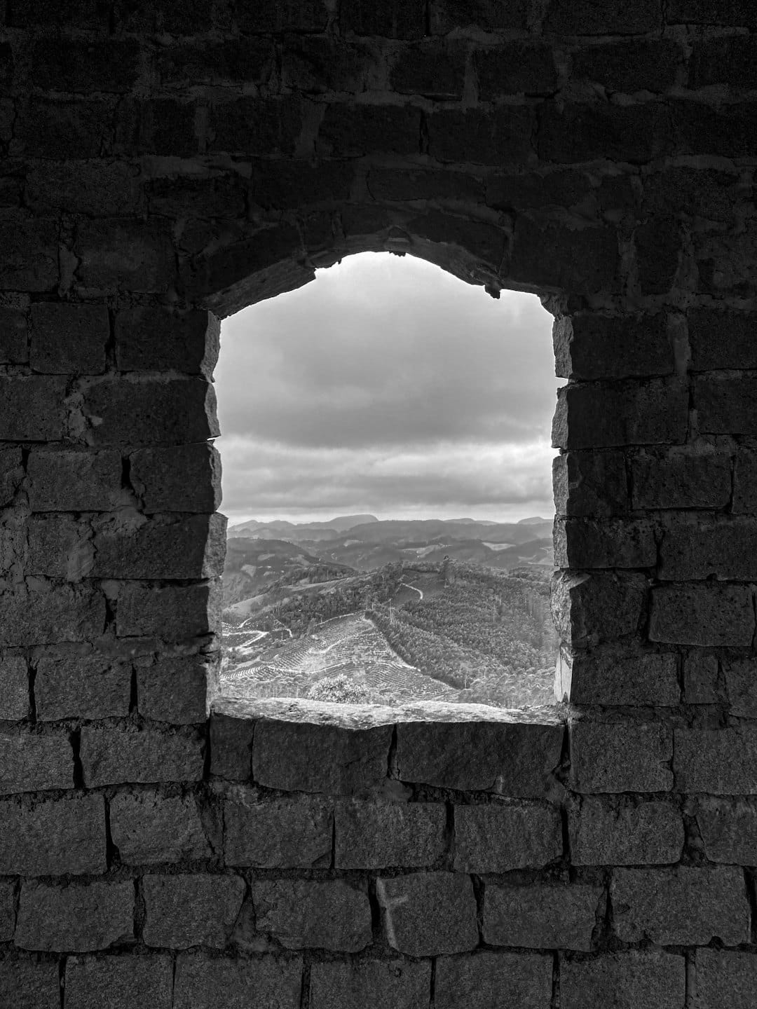 Rolling hills and terraced fields seen through a stone archway.