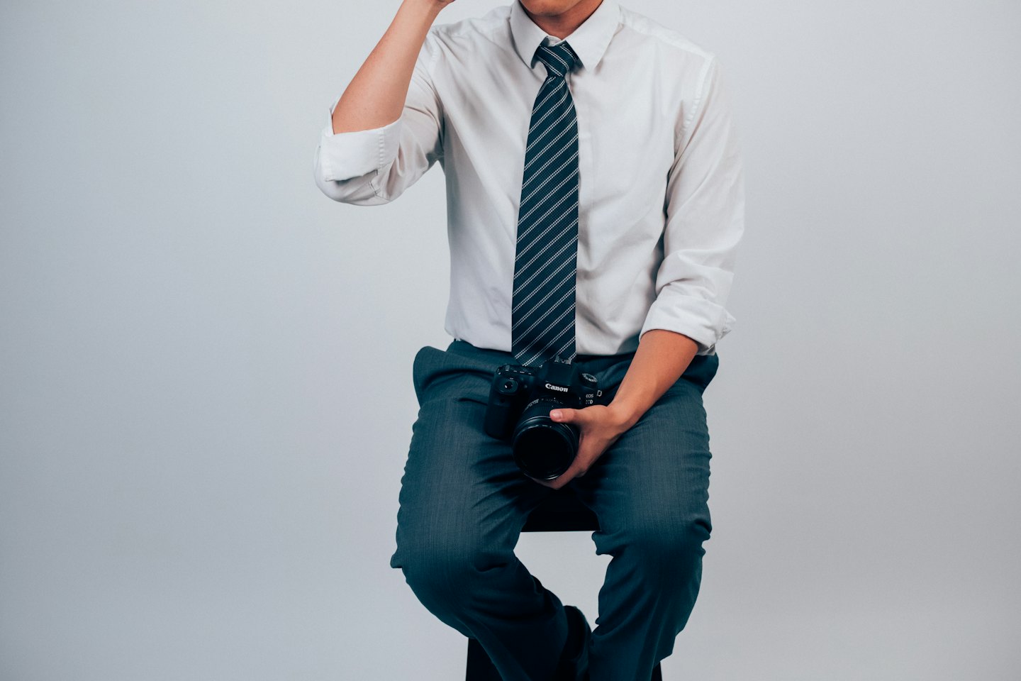 A man in a shirt and tie holds a camera.