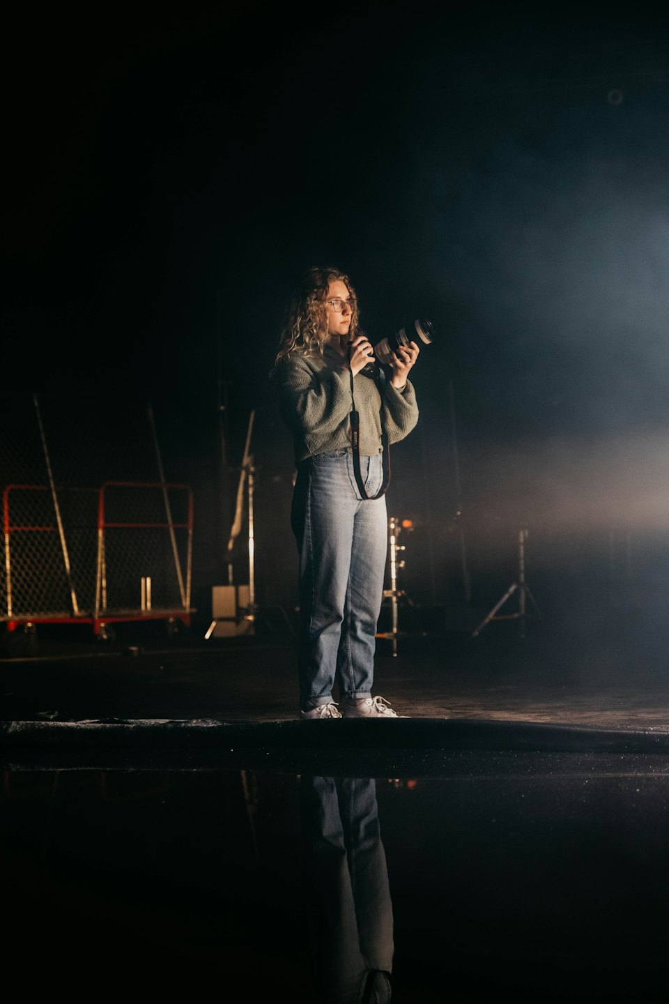 Photographer holding camera with lens reflection on floor.
