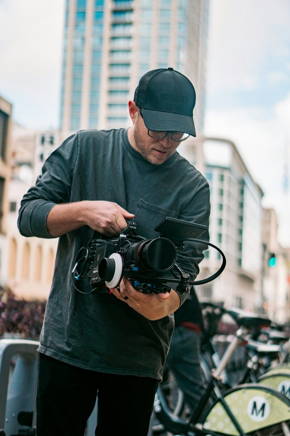 Man adjusting a professional video camera rig outdoors.