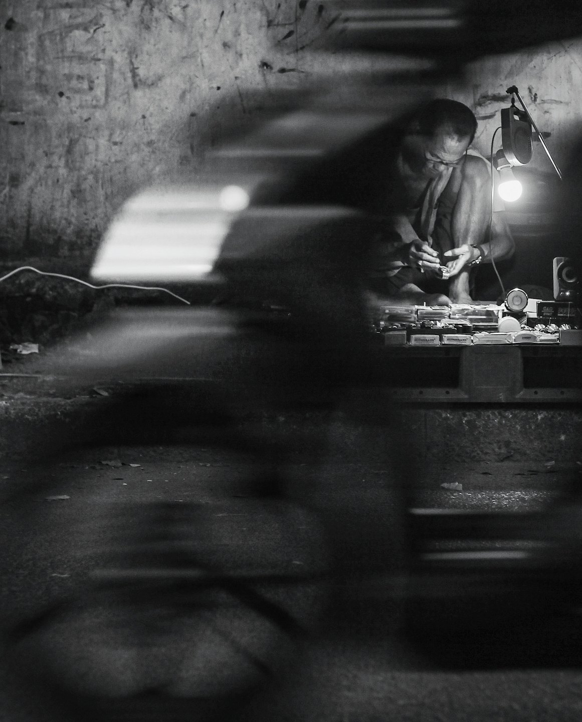 An elderly watchmaker works on small parts at his workbench.
