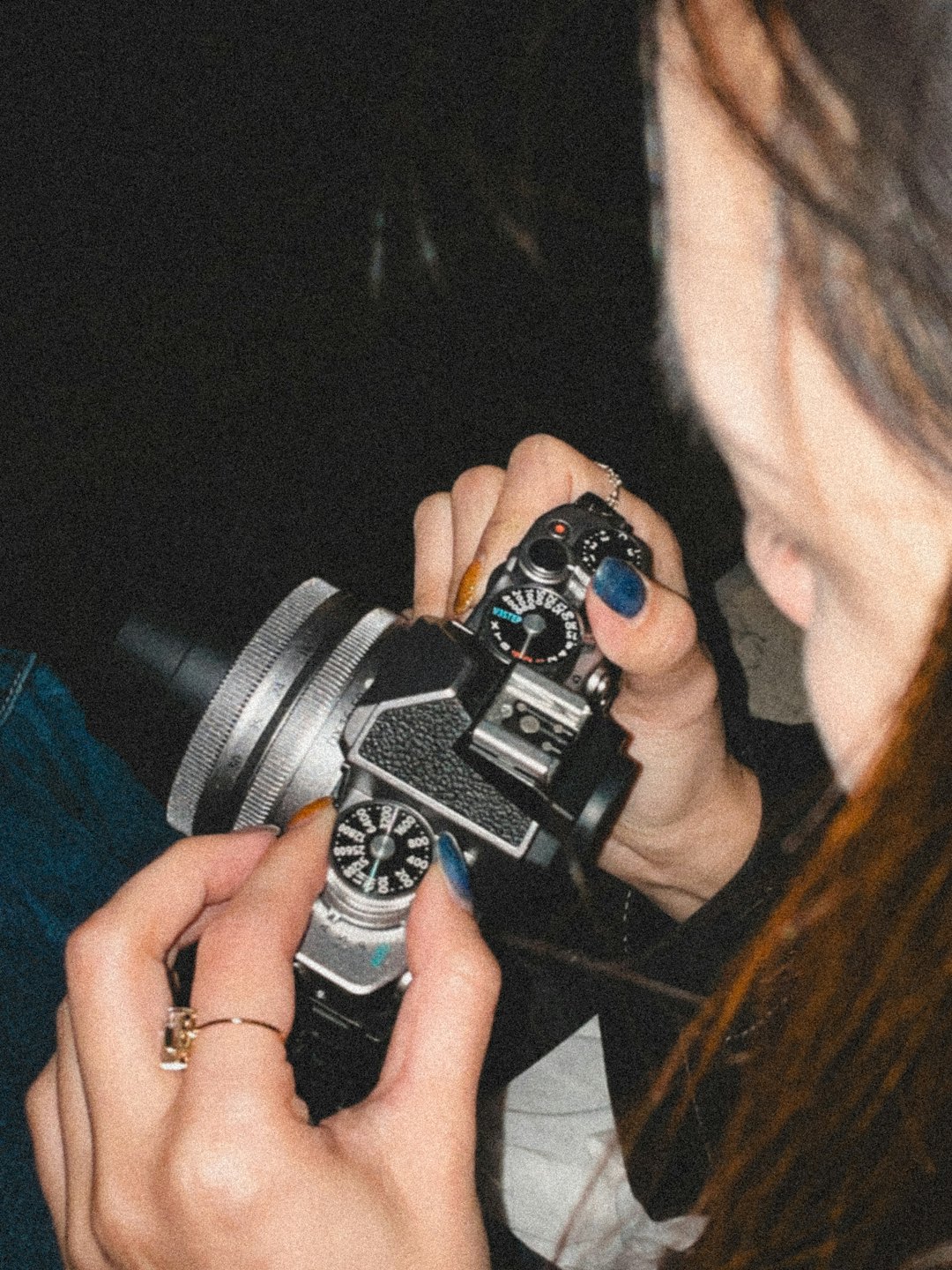 Hands adjusting the settings on a vintage camera.