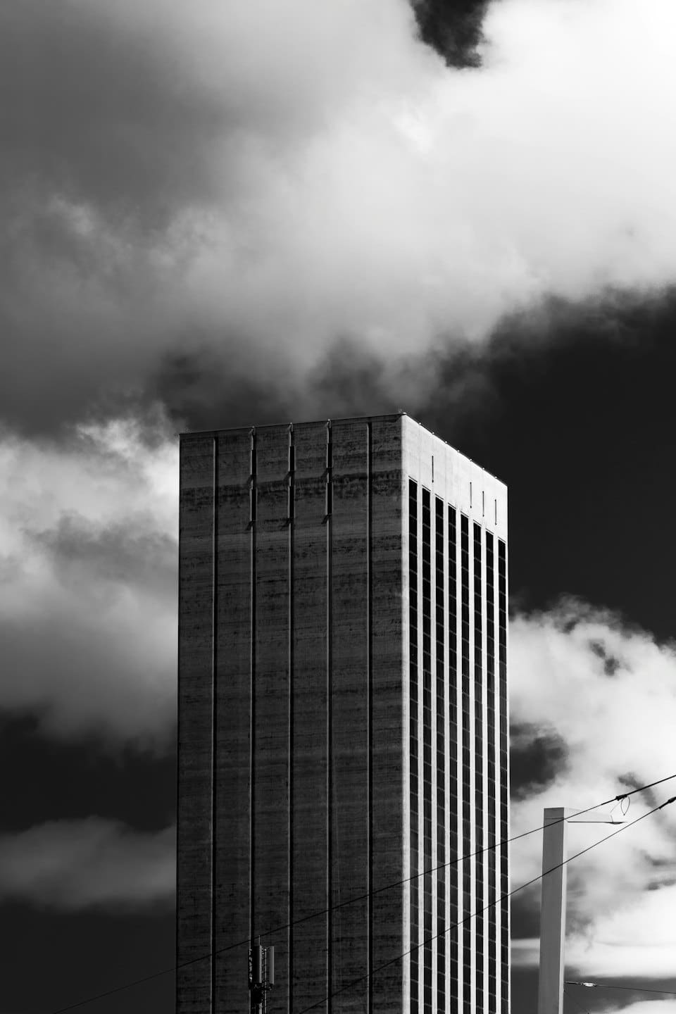 Tall concrete and glass building against a cloudy sky.